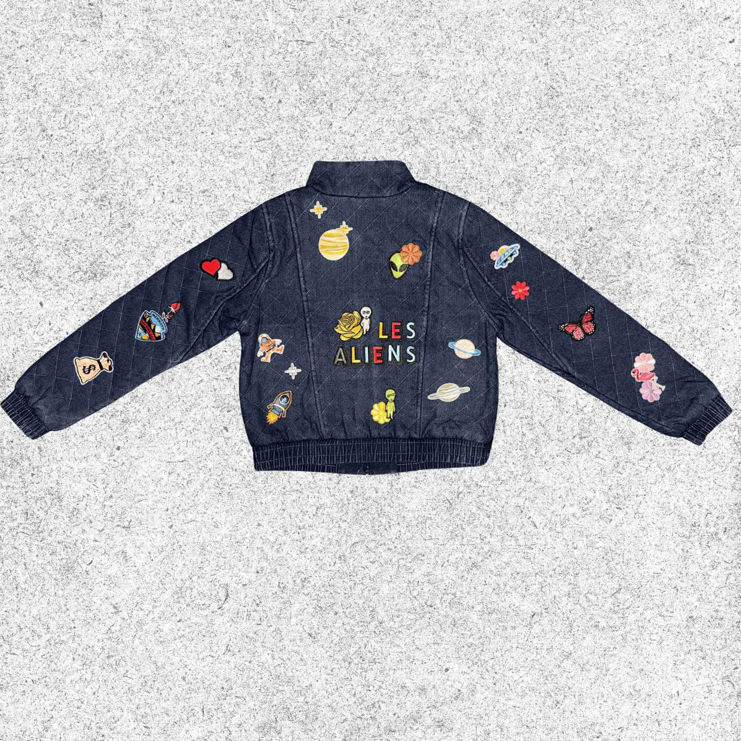 Denim jacket with colorful alien-themed patches back view.