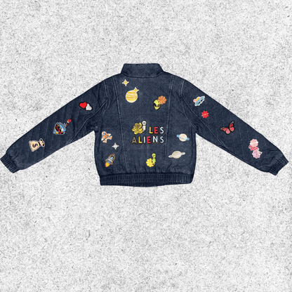 Denim jacket with colorful alien-themed patches back view.